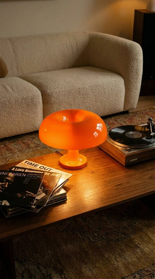 cosmic-orange-2 — Lampe Caldera orange allumée sur une table basse près d’une platine vinyle