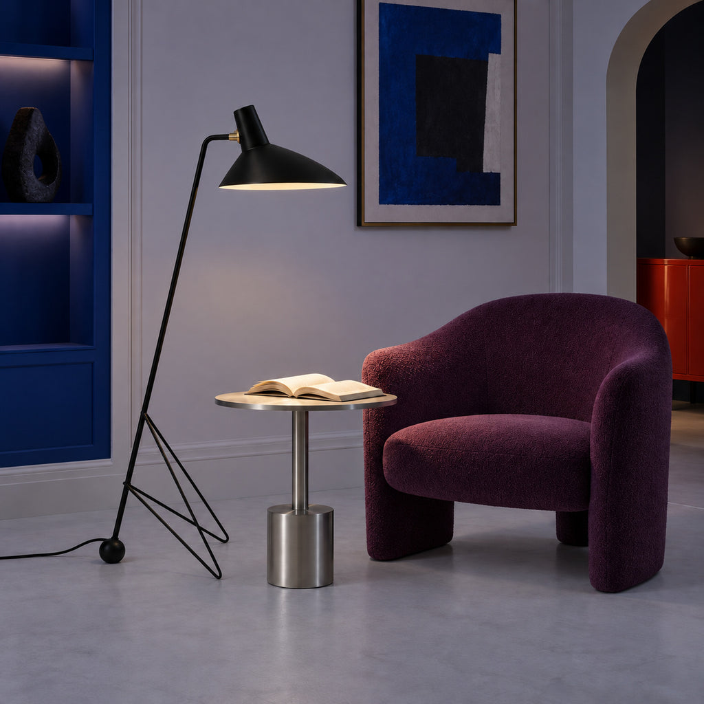 Lampadaire Trespolo allumé le soir près d’un fauteuil prune