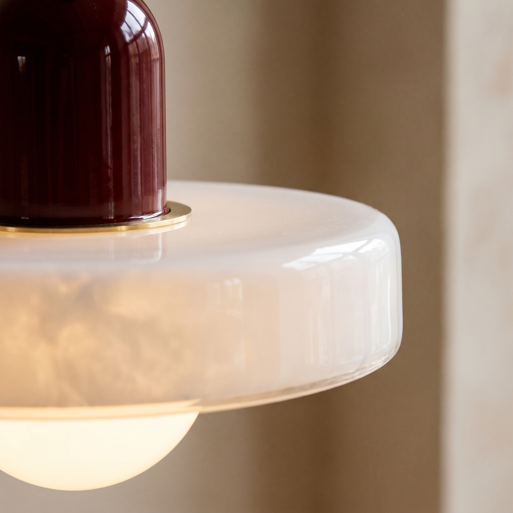 Détail du disque en verre opalin de la suspension Strata et de son capuchon bordeaux cerclé de laiton