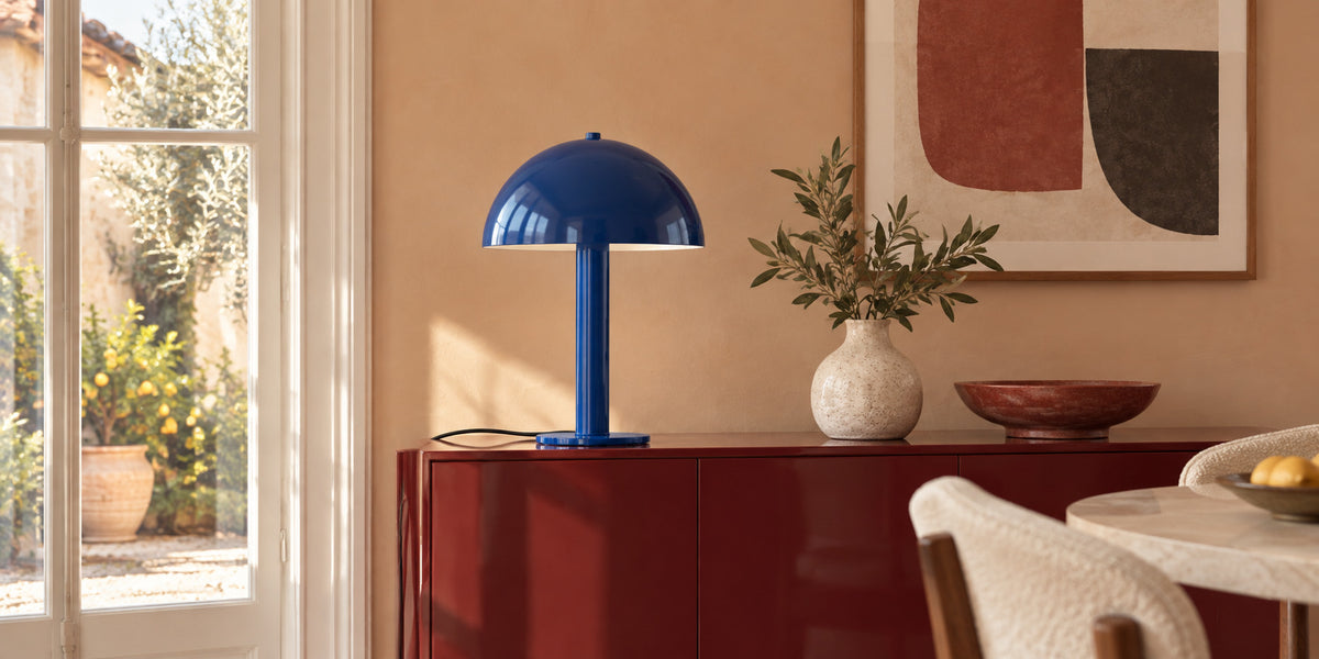 Lampe Lucca Pacific Blue sur un buffet laqué rouge, salle à manger ensoleillée, ambiance