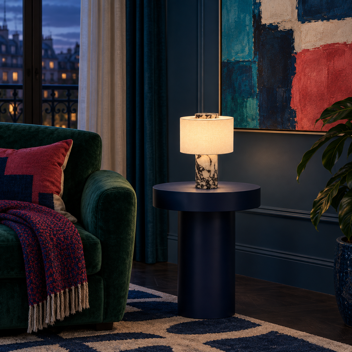 Lampe Obole allumée sur un guéridon bleu nuit, le soir